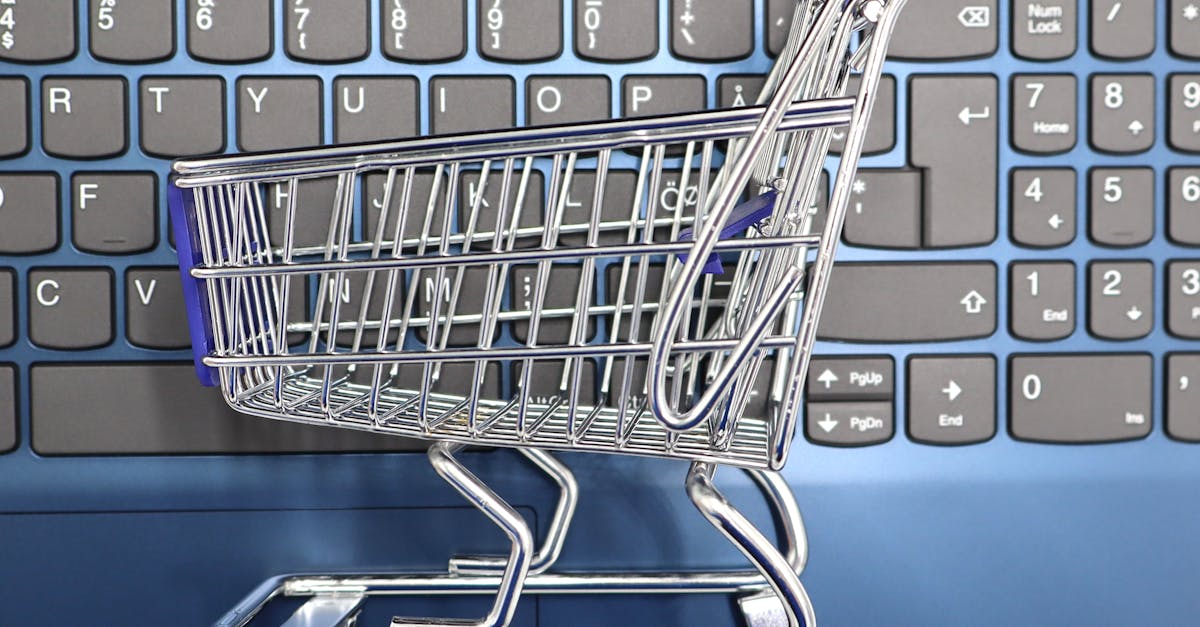 Een miniatuurwinkelwagentje op een laptoptoetsenbord, symbool voor online winkelen en e-commerce.